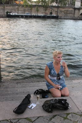 Nikole sipping champagne with the Seine river behind her