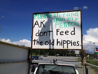 A sign reading, "Please stop and sign my petition. AK don't feed the old hippies."