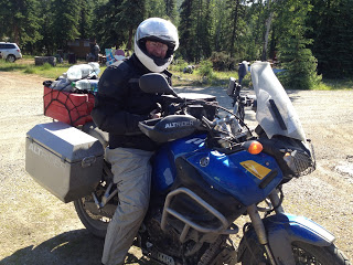A man wearing a helmet and sitting atop a very packed motorcycle