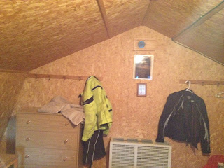 Inside of a rustic cabin with a dresser and two motorcycle jackets hanging