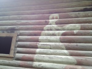 A ghost painted on the side of a log cabin