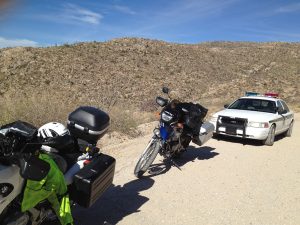 Image of two motorcycles on the side of the road with a cop car parked behind