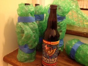 Image of a Monk's Mistress bottle with several bubble wrapped bottles in the background
