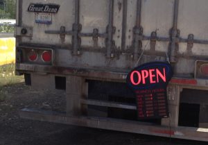 Image of an OPEN sign attached to the back of a semi truck