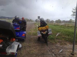 Image of Gene, Arlene, and Michael stopped on their motorcycles with a snowy sky in the background
