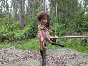 Image of a barbie doll tied to a post 