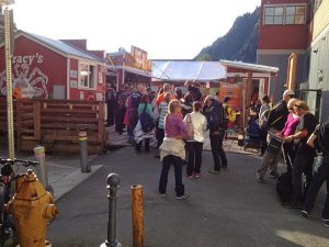 Image of a line of people outside of a red crab shack with a sign reading, "Tracey's"